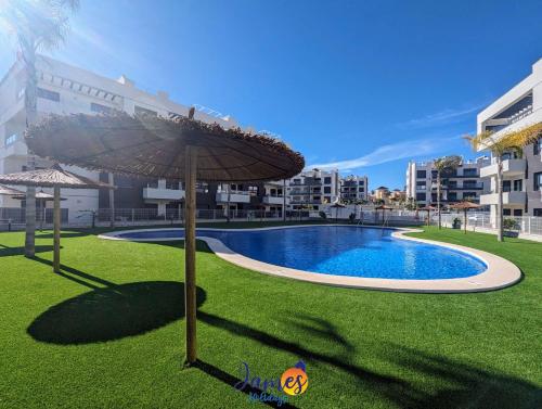 a swimming pool with an umbrella and some buildings at Luxury penthouse with Solarium and Com Pool VM78 in Villamartin