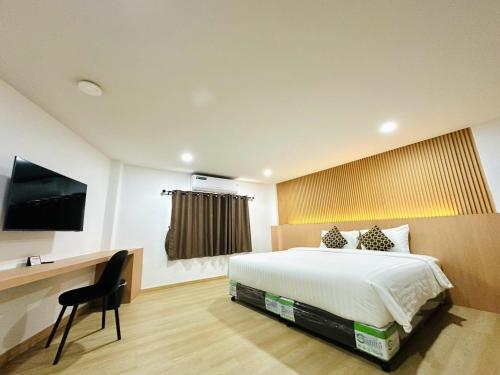 a bedroom with a bed and a desk and a television at The Cozy 77 in Bangkok