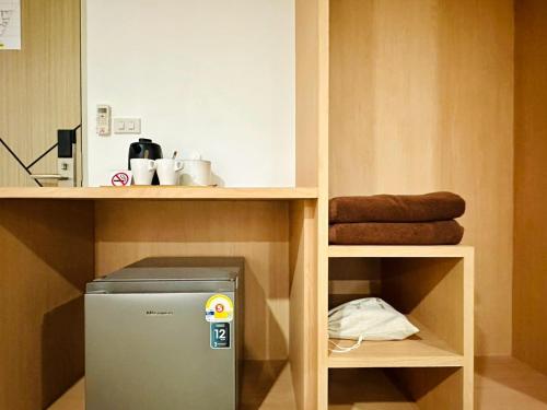 a small refrigerator under a shelf in a kitchen at The Cozy 77 in Bangkok