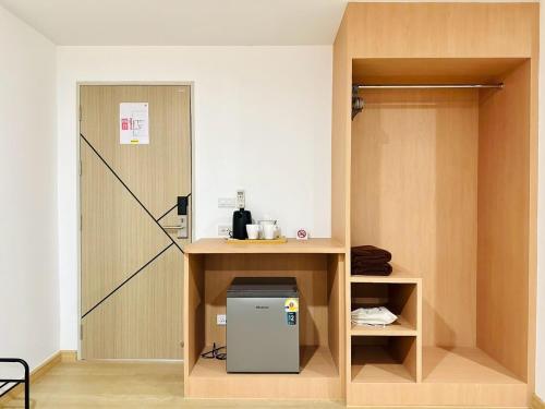 a room with a small refrigerator under a shelf at The Cozy 77 in Bangkok