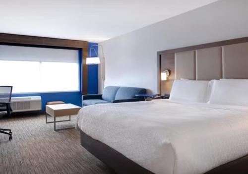 a hotel room with a large bed and a chair at Holiday Inn Express & Suites - Detroit - Dearborn by IHG in Dearborn
