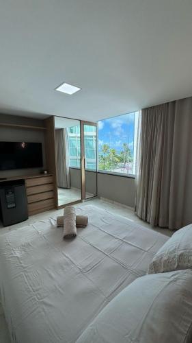 a bedroom with a large white bed and large windows at Flat luxury hotel cove in Maceió