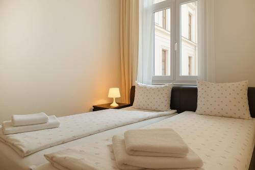 two beds in a small room with a window at Gozsdu Court Budapest in Budapest