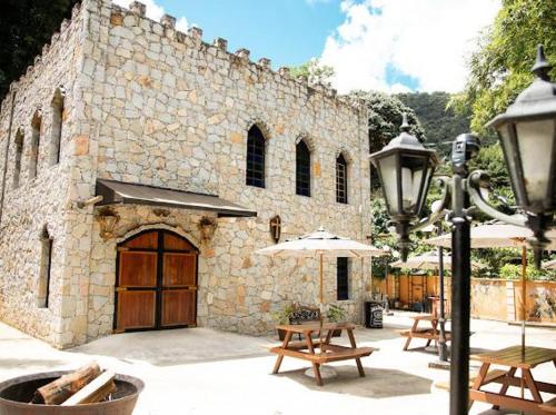 a stone building with tables and an umbrella at Apart-hotel Cantinho da Serra in Nova Friburgo