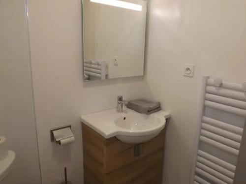a white bathroom with a sink and a mirror at Gite 7 Séjour au Puy Mary Gîte Confortable pour des Vacances Inoubliables in Le Claux