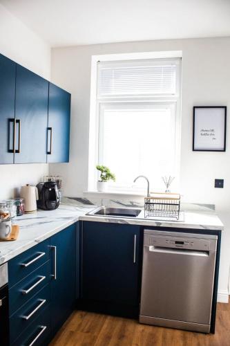 a kitchen with blue cabinets and a sink and a window at Victoria Lodge in Haworth