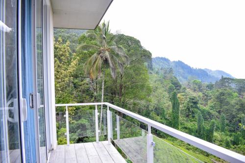 a balcony with a view of a palm tree at Flaming Tree Resorts in Kiriwan Eliya