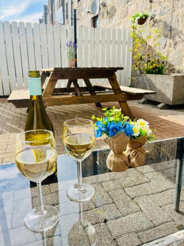 two glasses of white wine and a bottle on a table at Central, Modern Apartment - Private Terrace - Dog Friendly in Aberdeen