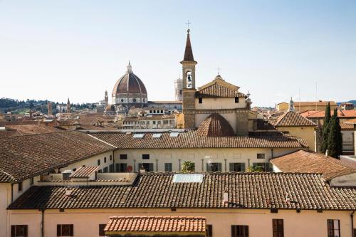 Blick auf eine Stadt mit einem Uhrturm und Dächern in der Unterkunft Hotel Panorama in Florenz