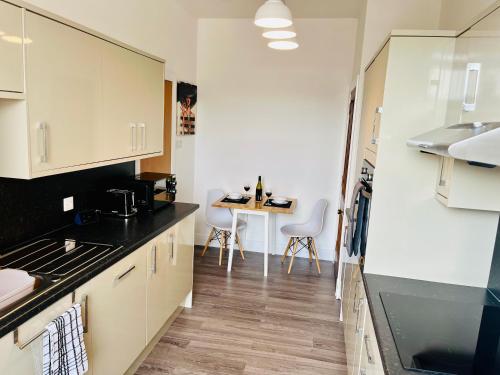 a kitchen with white cabinets and a table with chairs at Central, Modern Apartment - Private Terrace - Dog Friendly in Aberdeen