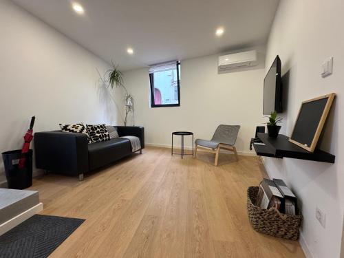 a living room with a black couch and a tv at Living PDL 1 in Ponta Delgada