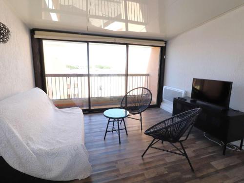 une chambre avec un lit, une télévision et une chaise dans l'établissement Splendide 3 pièces climatisé avec 3 terrasses, proche mer, parking sécurisé - FR-1-307-135, au Grau-du-Roi