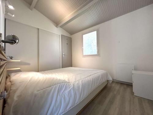 une chambre avec un grand lit blanc avec une fenêtre dans l'établissement Maison cosy avec mezzanine, piscine chauffée, proche mer - 4 couchages - parking privatif - FR-1-224A-1, à Bretignolles-sur-Mer