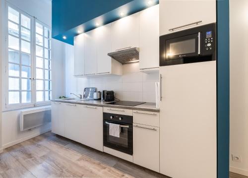 une cuisine avec des armoires blanches et un micro-ondes dans l'établissement Le Palais des Guilhem, à Montpellier