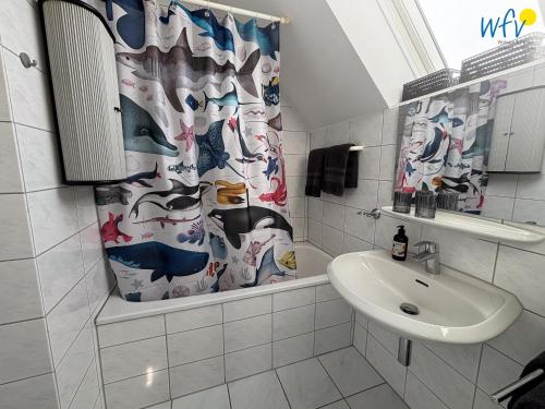 une salle de bain avec un lavabo et un rideau de douche dans l'établissement Haus Nordstern Ferienwohnung Hummerhütte, à Juist