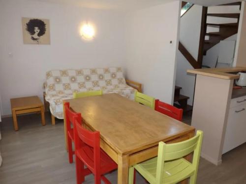 a kitchen with a wooden table and colorful chairs at Gite 8 Vacances en Auvergne Gîte au Puy Mary avec Activités de Plein Air in Le Claux
