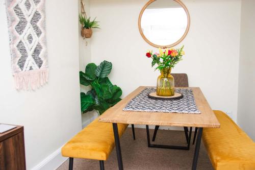 a table with a mirror and a vase with flowers at Beautiful Character 3 Bed City Centre Apartment in Bath