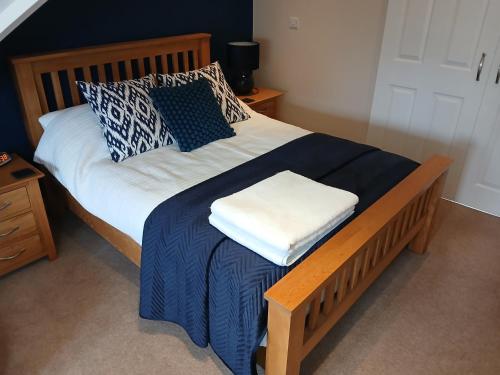 a bed with a blue and white blanket and pillows at The Herons in Goldsborough