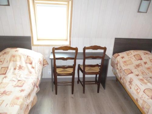 a bedroom with two beds and a table and two chairs at Auberge des Etangs in Roussent