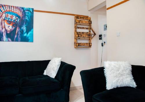 a living room with a black couch and a painting at Afrikim Apartment Kahawa Sukari in Nairobi