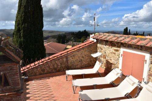 a patio with white chairs on a brick wall at GiuMa Tuscany Historic Country House with Roof Terrace near Saturnia Spa in Montemerano