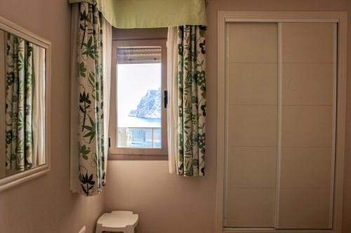 a bathroom with a toilet and a window at Apartamentos Esmeralda Suites Unitursa in Calpe