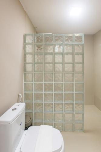 a bathroom with a toilet and a tiled wall at Pousada Vila Flow in Cumbuco
