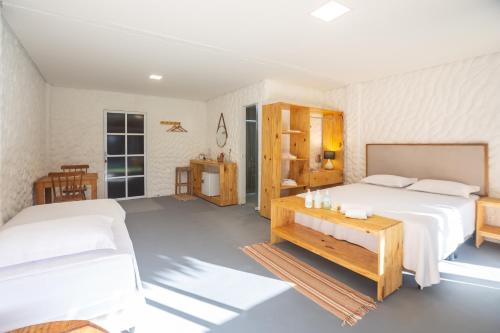 a white bedroom with two beds and a table at Pousada Vila Flow in Cumbuco