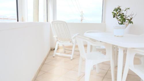 a white dining room with white chairs and a table at Cataldo Guest House in Capri