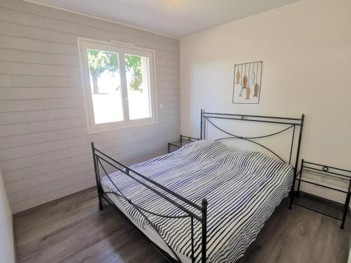 une chambre avec un lit dans une pièce avec une fenêtre dans l'établissement Villa avec son Lodge - Piscine Lagune - 10 personnes, à Linxe