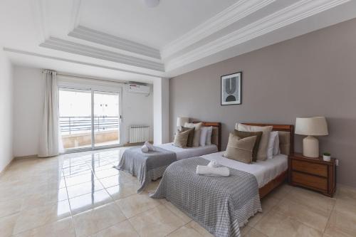 a white room with two beds and a window at Appartement 4 pièces à Bir Mourad in Birmandreis