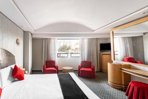 a hotel room with a bed and red chairs at Capital O Andrade, Mexico City in Mexico City