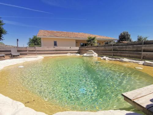 une grande piscine d'eau en face d'une maison dans l'établissement Villa avec son Lodge - Piscine Lagune - 10 personnes, à Linxe