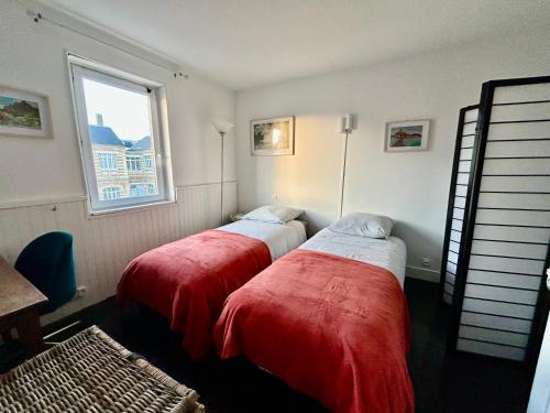 deux lits dans une chambre avec une fenêtre dans l'établissement La maison des écoliers, à Deauville