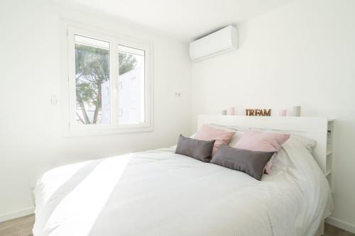 une chambre blanche avec un grand lit blanc avec des oreillers dans l'établissement La Ciotat T2 Climatisé Plage Lumière avec garage, à La Ciotat