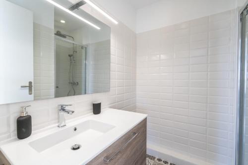 une salle de bain blanche avec un lavabo et un miroir dans l'établissement La Ciotat T2 Climatisé Plage Lumière avec garage, à La Ciotat