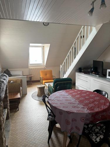 un salon avec une table et des chaises et un escalier dans l'établissement Studio les Mouettes, à Perros-Guirec