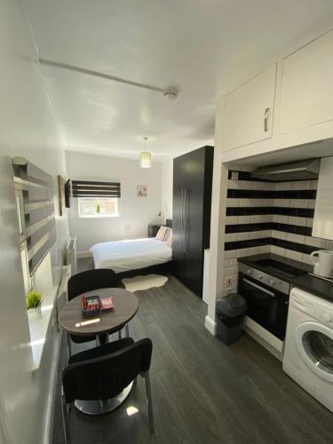 a small apartment with a bed and a table and chairs at Whitehorse's Gated Studio Apartment in Thornton Heath