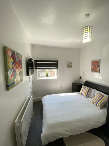 a bedroom with a large white bed and a window at Whitehorse's Gated Studio Apartment in Thornton Heath