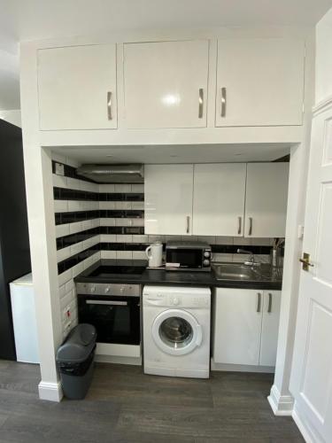 a white kitchen with a stove and a dishwasher at Whitehorse's Gated Studio Apartment in Thornton Heath