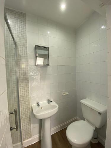 a white bathroom with a toilet and a sink at Whitehorse's Gated Studio Apartment in Thornton Heath