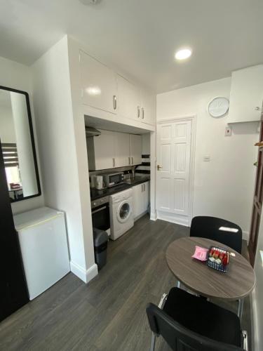 a living room with a table and a kitchen at Whitehorse's Gated Studio Apartment in Thornton Heath