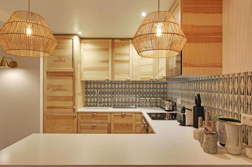 - une cuisine avec deux lustres et un comptoir blanc dans l'établissement 2 appartements en 1 - Superbe logement près du Louvre l 12P, à Paris