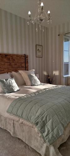 - une chambre avec un grand lit et un lustre dans l'établissement Logis du Poirier, à Juignac