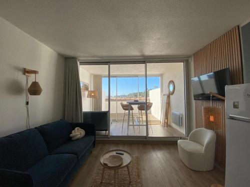 un salon avec un canapé bleu et une table dans l'établissement Studio cosy et rénové - vue port, à Capbreton