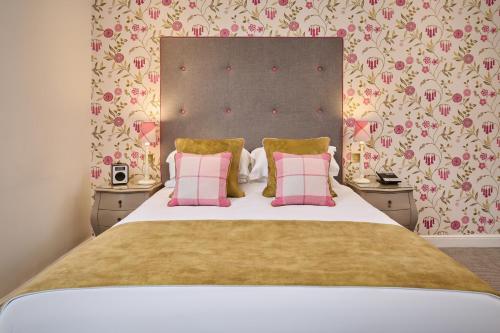 a bedroom with a large bed with two pink pillows at The Roseate Villa Bath in Bath