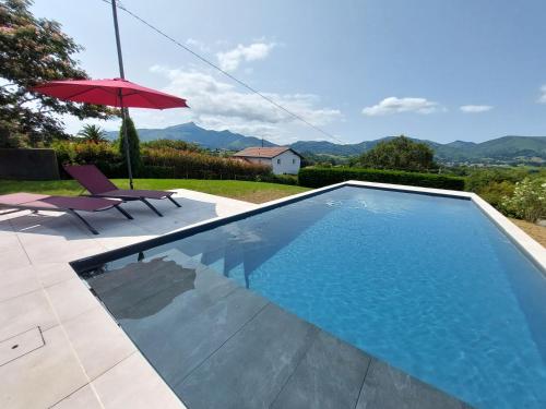 - une piscine avec une chaise et un parasol dans l'établissement Villa avec piscine vue montagnes à 3km des plages, à Urrugne