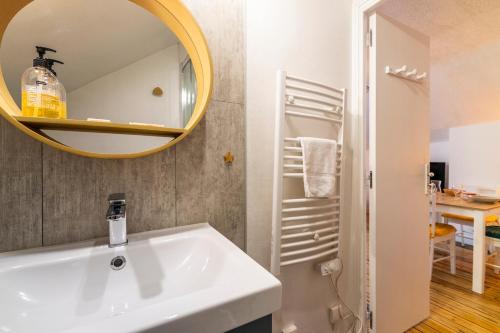 ein Badezimmer mit einem weißen Waschbecken und einem Spiegel in der Unterkunft Au cœur de la ville, traversant et tout confort in Vannes
