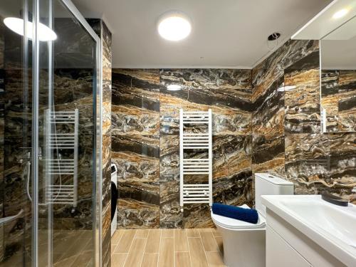 a bathroom with a stone wall with a toilet and a sink at Empire Apartment 4 in Néa Michanióna