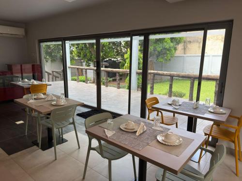 a dining room with tables and chairs and a large window at CasaNova Airport Suites in Accra